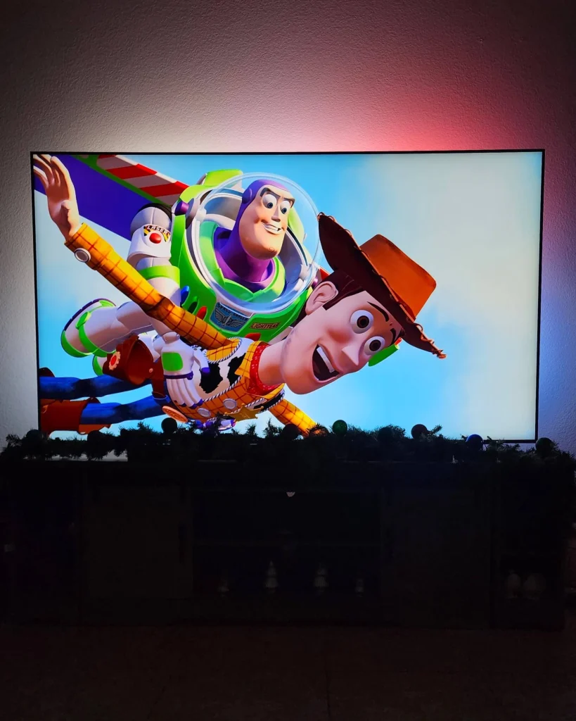 A TV screen showing Toy Story with Buzz Lightyear and Woody flying, with ambient Philips Hue lighting.