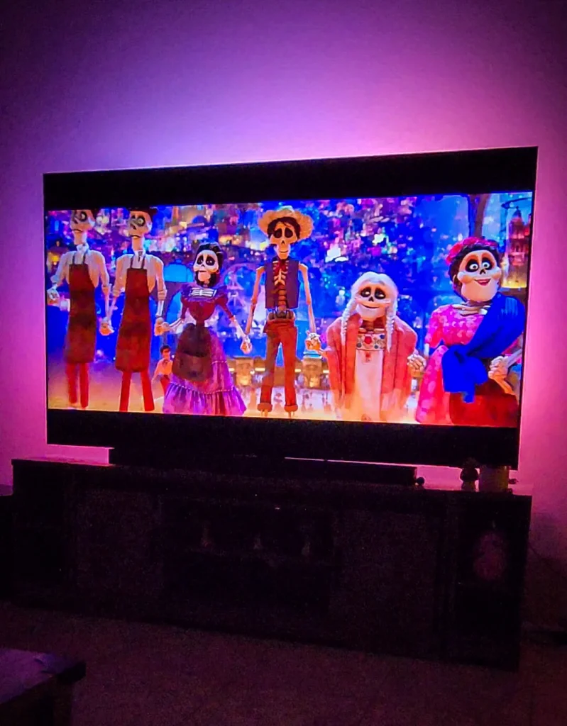 A living room with Coco playing on the TV, illuminated by vibrant Philips Hue lights syncing to the movie’s colors.